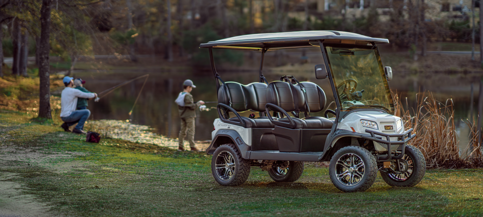 A white and black golf cart with tan seats parked on green grass